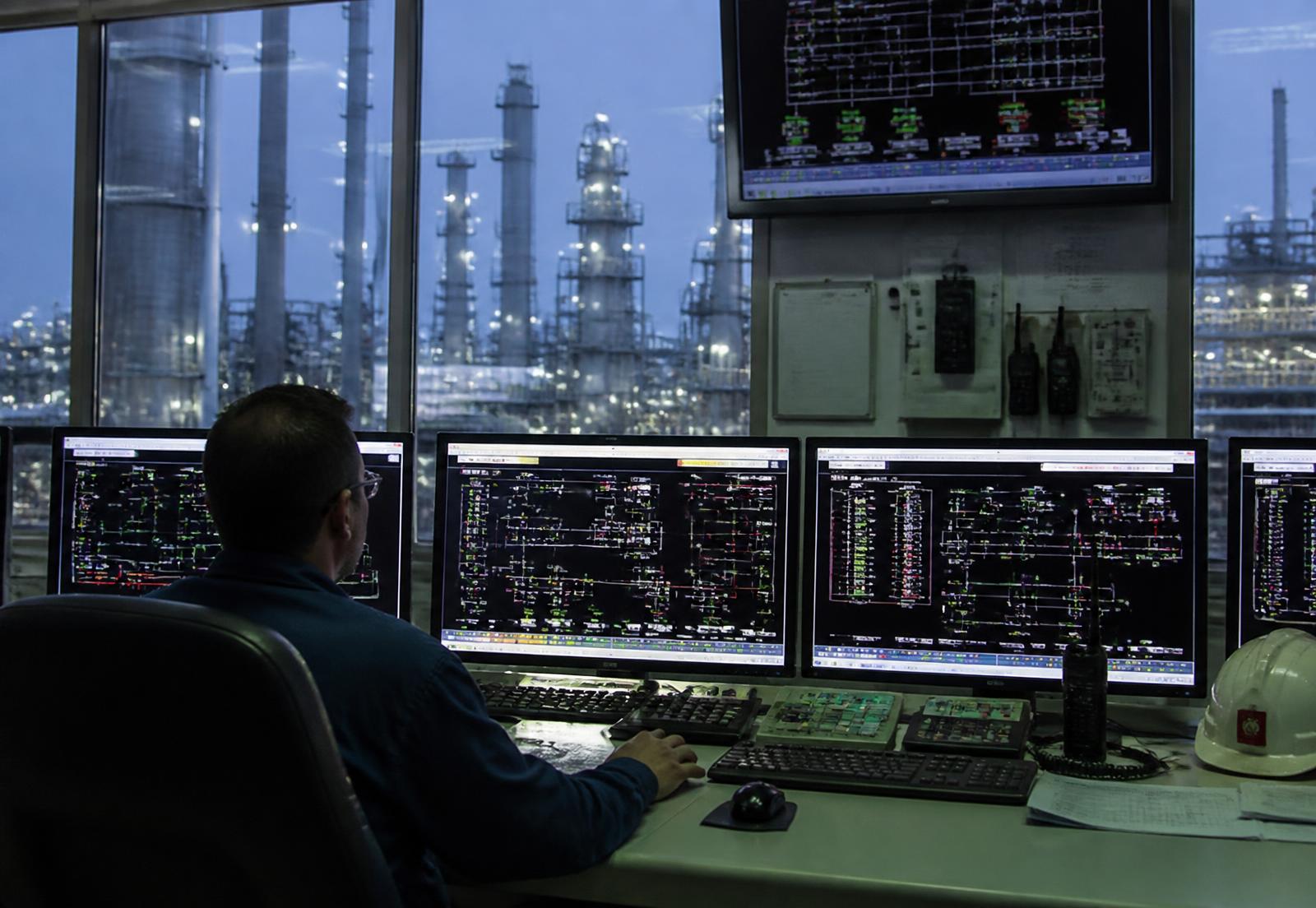 Sala de control industrial con pantallas de sistema DCS y válvulas motorizadas monitoreadas